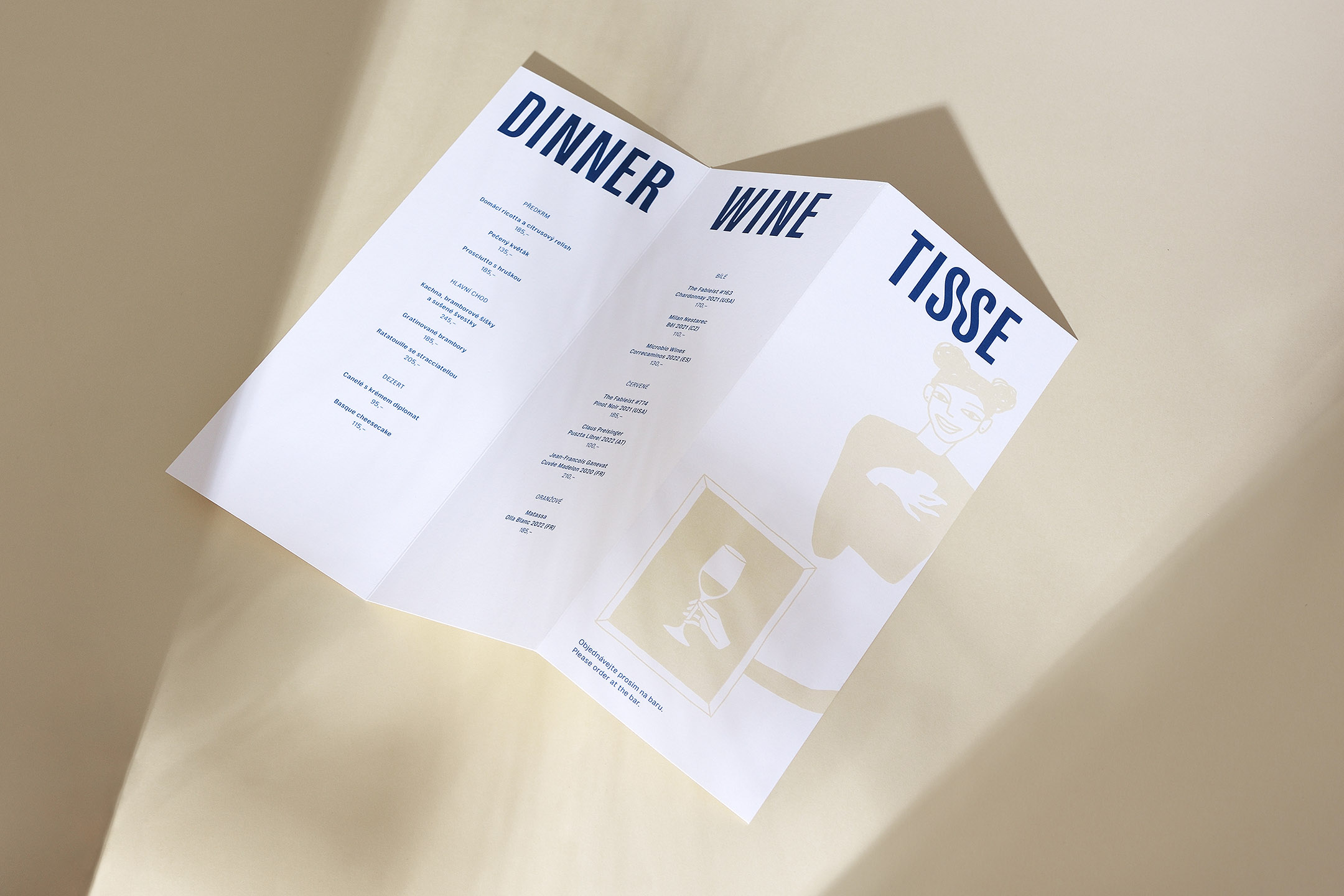 Tisse Menu rozlozene open laying flat on beige background with sharp shadows